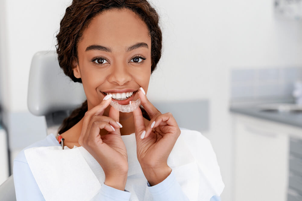 patient placing clear aligner into mouth